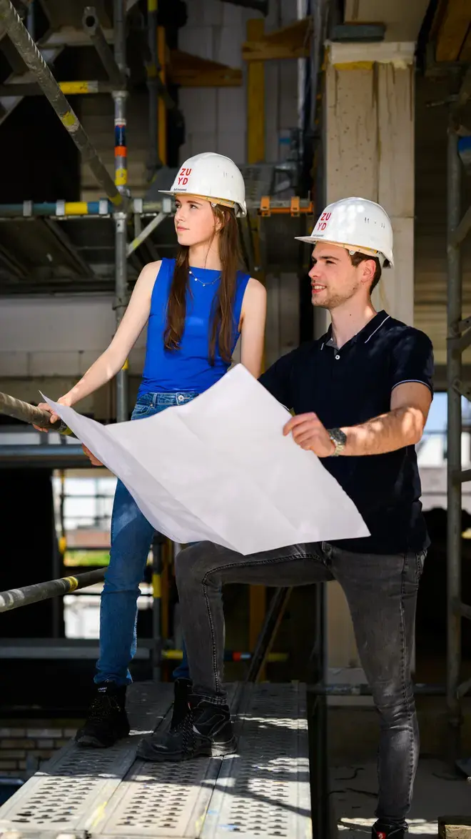 Built Environment - studenten met bouwtekening op steiger