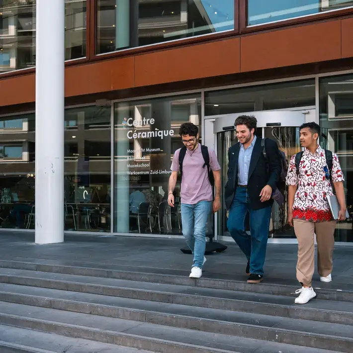 Drie studenten op een trap voor een gebouw