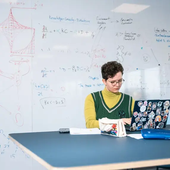 Persoon met laptop voor een whiteboard