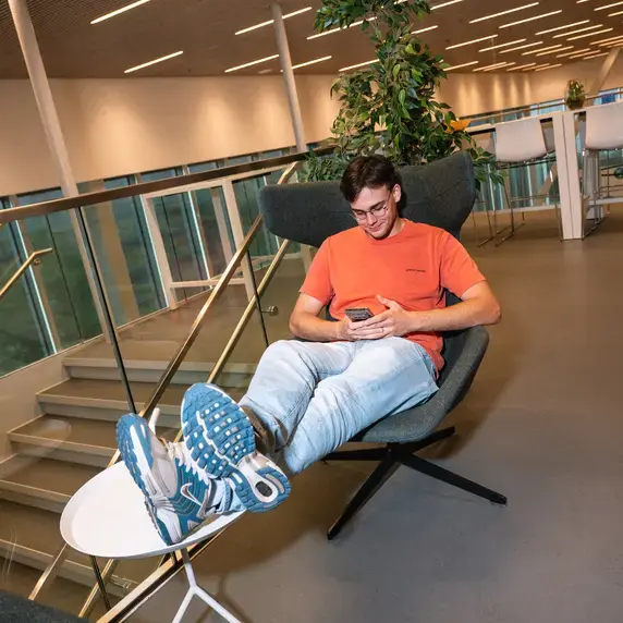 Applied Science - student met telefoon in luie stoel