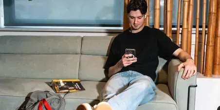 Technische-bedrijfskunde jongen op bank met telefoon