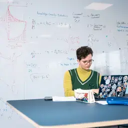 Persoon met laptop voor een whiteboard