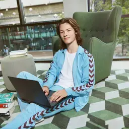Student zit op de grond met laptop en boeken